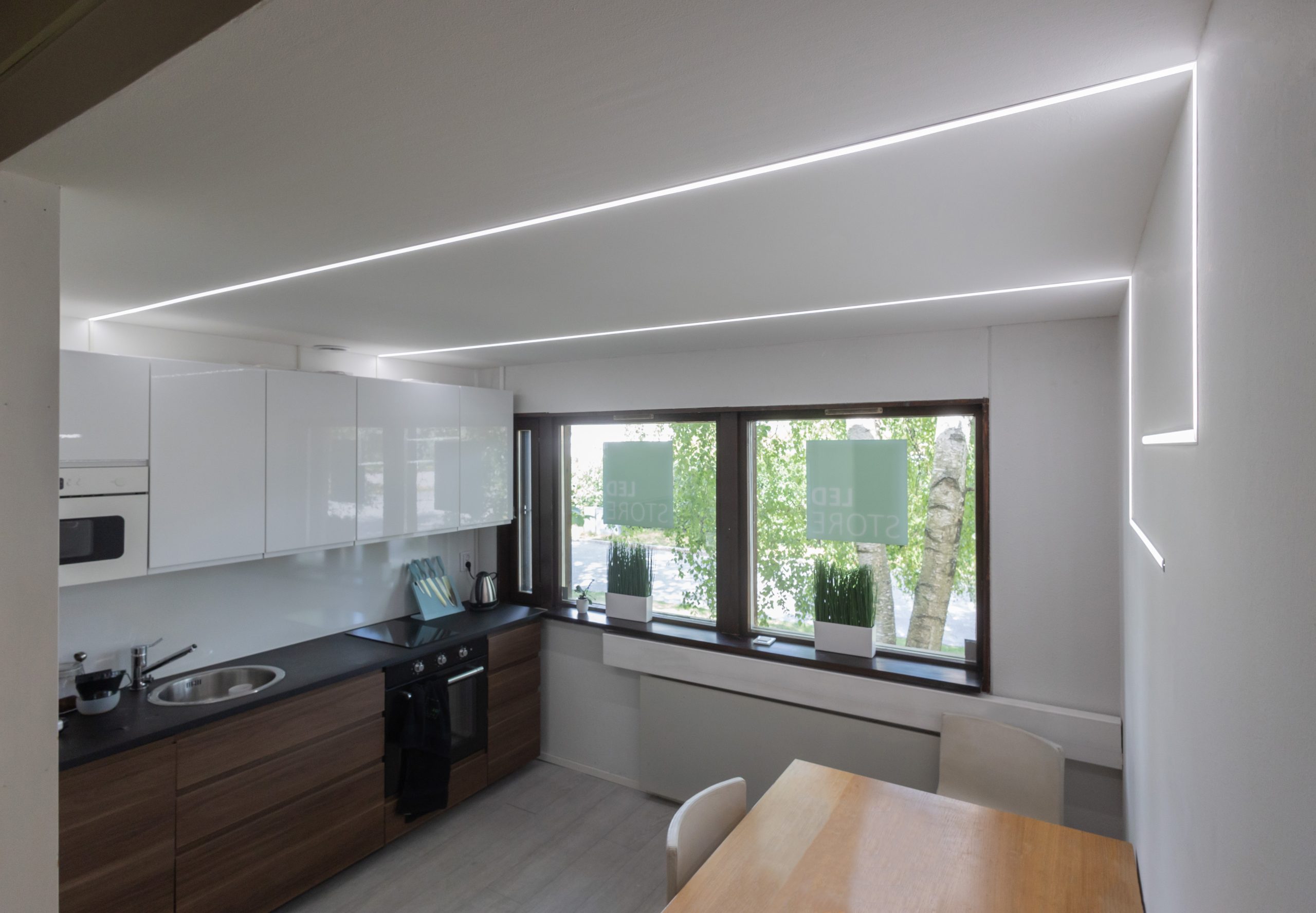 GZ9A6109 - LedStore Moderne Menschen sind anspruchsvoll und leistungsfähig, integrativ und hoch. Suuret ikkunat päästävät sisään runsaasti luonnonvaloa. Puinen ruokapöytä auf ympäröitynä valkoisilla tuoleilla. Minimalistische Design-Korostavat LedStore.fi:n lineaariset LED-kattovalaisimet sekä ikkunalaudalla olevat viherkasvit.