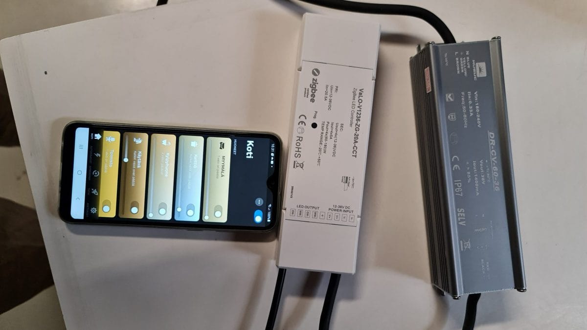 Älypuhelin, joka näyttää sovelluksen vierekkäin kahden kaapelilla varustetun elektronisen laitteen kanssa, tarjoaa teknisiä tietoja kuten "Zigbee" ja "ROHS". Puhelimen käyttöliittymä sisältää erilaisia ohjausvaihtoehtoja, mukaan lukien LED-asetukset.