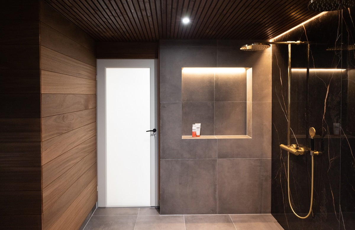 Led-nauha katon urassa sekä shampoohyllyn yläreunassa antavat kylpyhuoneeseen pehmeän yleisvalon. Lisänä kiinteät, vesitiiviit 9W spotit. © LedStore.fi