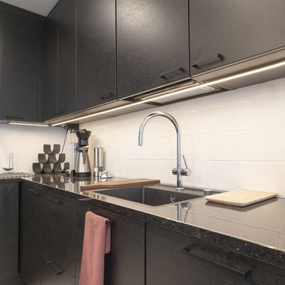 L'illuminazione a LED della cucina mette in risalto i mobili neri e il lavello cromato e migliora l'illuminazione del moderno spazio di lavoro.