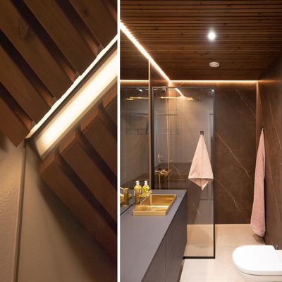 Un bagno moderno, illuminato da una luce LED a soffitto, che mette in risalto i mobili e gli accenti in legno naturale.