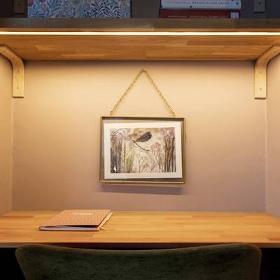 Una scrivania dotata di un'illuminazione LED d'atmosfera sotto il ripiano e una lampada da parete che mette in risalto l'opera d'arte raffigurante un uccello con un'illuminazione d'accento.