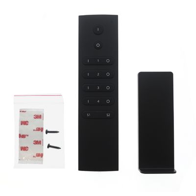 Testo alternativo: 'Telecomando nero con supporto a parete, viti e nastro per l'installazione di luci a LED con sfondo bianco.