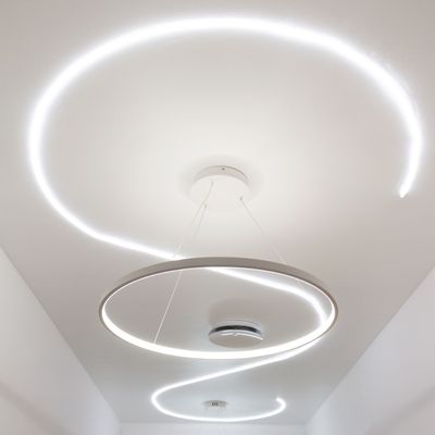 Il motivo a spirale delle moderne plafoniere circolari a LED su un tetto bianco esalta il design dell'illuminazione moderna.