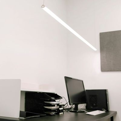 Ambiente d'ufficio moderno con illuminazione a LED a risparmio energetico, elegante scrivania nera, monitor per computer e vassoi per la carta organizzati.