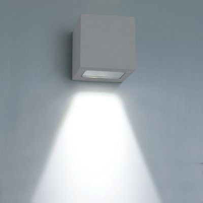 L'applique LED a forma di cubo illumina un fascio luminoso verso il basso su una parete blu tenue e accentua gli interni moderni con un'illuminazione a risparmio energetico.