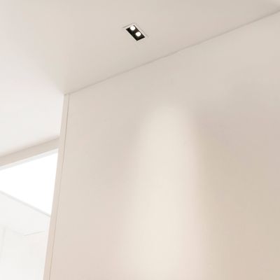 Una stanza minimalista con soffitto e pareti bianche e un elegante apparecchio LED rettangolare da incasso per un'illuminazione moderna.