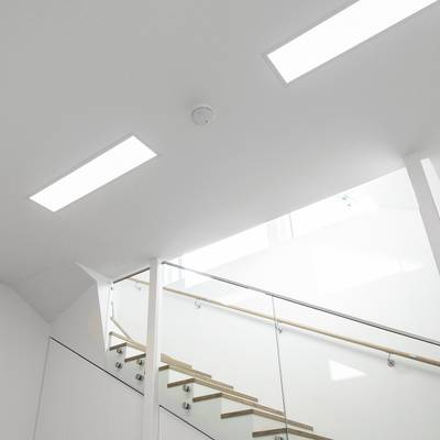 Le moderne lampade da soffitto a LED illuminano intensamente le pareti bianche della scala e della ringhiera in vetro.