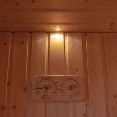 Espositore da parete con pannello in legno, piccola luce illuminata a LED e piastrella in legno con termometro e igrometro incorporati per un'atmosfera domestica moderna.