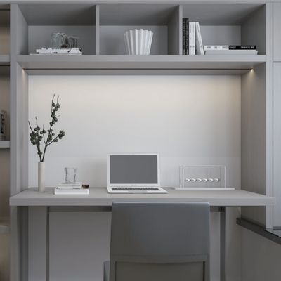 Un ufficio domestico minimalista con illuminazione a LED ad alta efficienza energetica, un elegante computer portatile su una scrivania, una comoda sedia ed eleganti scaffali con libri e decorazioni.