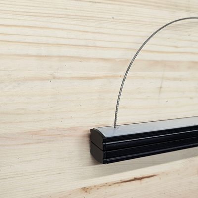 Lampada a sospensione in metallo nero con montatura in metallo esposta su una parete in legno chiaro in un negozio di illuminazione a LED.