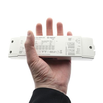 In mano, un dispositivo rettangolare bianco che riporta informazioni tecniche e simboli e la parola "Zigbee" associata alla tecnologia di illuminazione a LED.