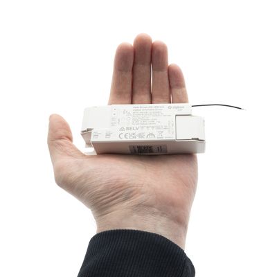 Una persona tiene in mano un comando di luce a LED che mostra dimensioni e funzioni, mettendo in mostra la moderna tecnologia di illuminazione in un negozio.