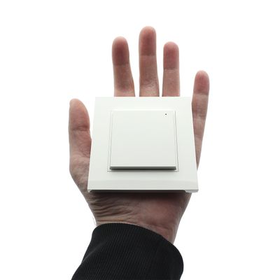 Mano quadrata, interruttore della luce moderno su sfondo bianco, che simboleggia il controllo avanzato dell'illuminazione a LED. Ideale per il design di una casa contemporanea.