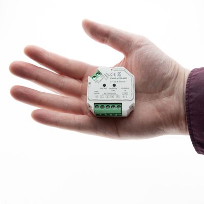 Primo piano di una persona che tiene in mano un componente di illuminazione a LED con connettori, ideale per soluzioni di illuminazione ad alta efficienza energetica, su uno sfondo bianco.