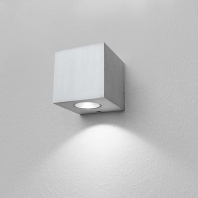 Un'applique LED quadrata e minimalista che crea una calda luce su un'elegante parete bianca, perfetta per gli interni moderni.