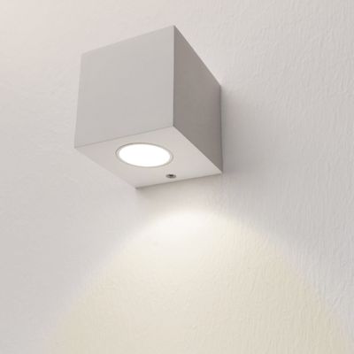 Testo alternativo: l'applique LED a forma di cubo illumina una luce bianca morbida su una parete strutturata, un design moderno per la casa o l'ufficio.