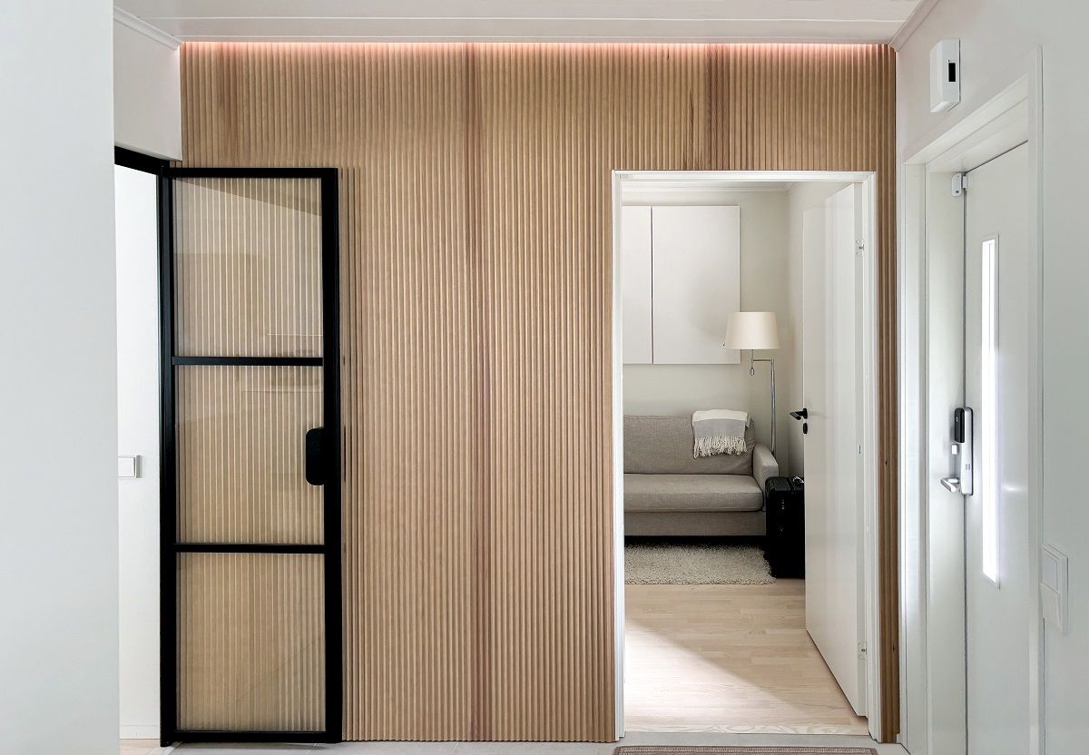 Nel corridoio, una striscia di luce a led nella scanalatura tra il pannello a parete e il soffitto crea un'atmosfera morbida nello spazio, con un tono di luce neutro