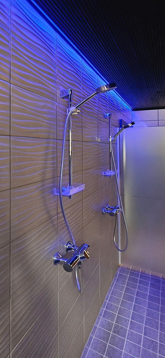 I bagni sul lato maschile sono illuminati con strisce RGB che partono dal soffitto sopra le docce, foto di The Goonies