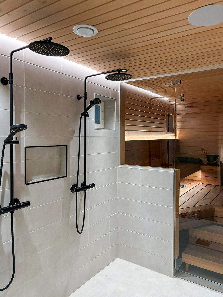 Dietro le docce, una striscia luminosa a LED inserita in una scanalatura nella linea del soffitto illumina indirettamente la parete fino al pavimento. La luce è efficiente e gradevole alla vista. © LedStore.fi