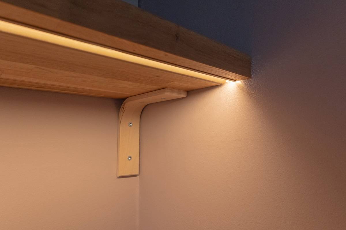 Primo piano di un profilo incassato nella parte inferiore di uno scaffale. Il colore del profilo è rame opaco.