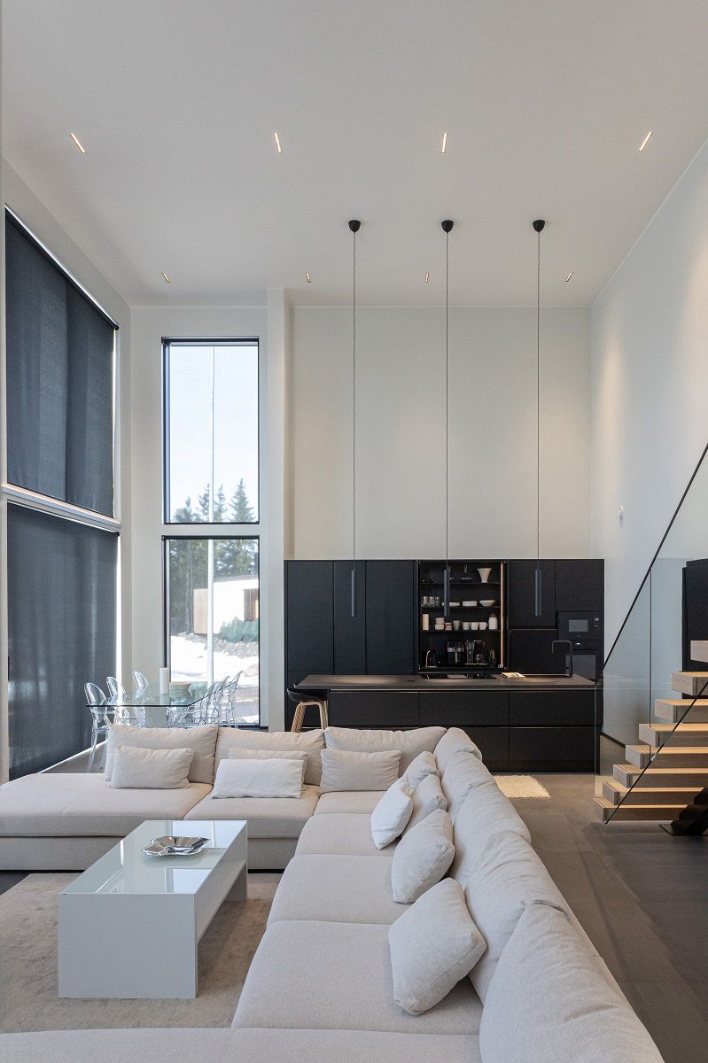 Faretti LINJA10 per l'illuminazione generale nel soffitto del soggiorno, della cucina e della sala da pranzo, e tre luci a sospensione LED PIIPPU 2.0 sopra l'isola della cucina.