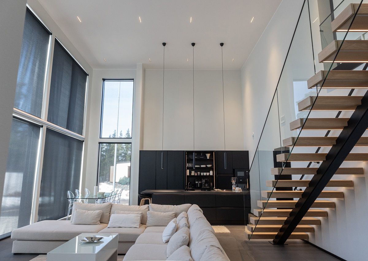 Faretti LINJA10 per l'illuminazione generale nei soffitti alti del soggiorno, della cucina e della zona pranzo, e tre luci a sospensione LED PIIPPU 2.0 sopra l'isola della cucina. Striscia LED sui gradini delle scale.