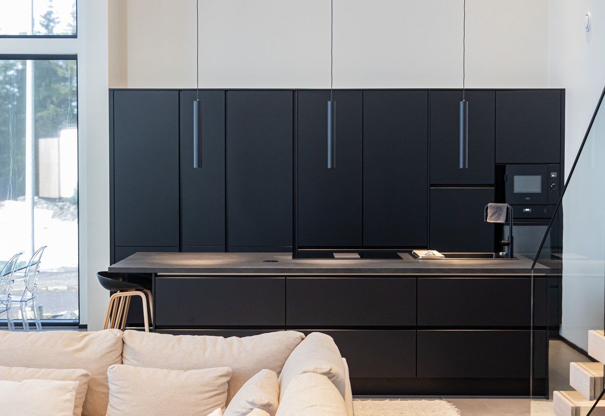 Tre luci a sospensione PIPPEU 2.0 nere sopra un'isola da cucina nera