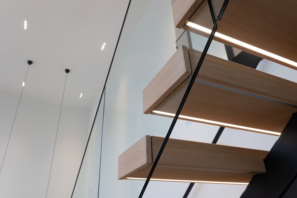 Sotto la pedata delle scale, striscia led montata a filo del profilo. Spot led LINJA10 sullo sfondo del soffitto.