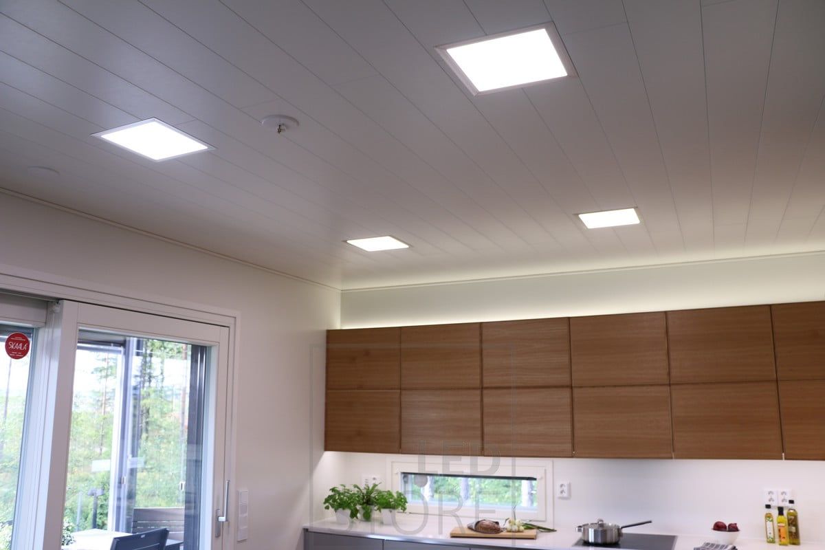 Luci a pannello sul soffitto, illuminazione indiretta sui mobili e una striscia a led che illumina il piano della cucina. Ledstore.fi