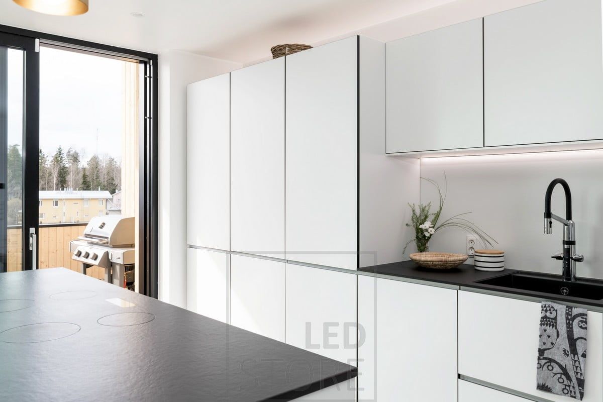 In cucina, una striscia LED nella parete divisoria illumina il piano della cucina dal fondo dei mobili superiori. La striscia a LED funge da eccellente luce per cucinare. Ledstore.fi