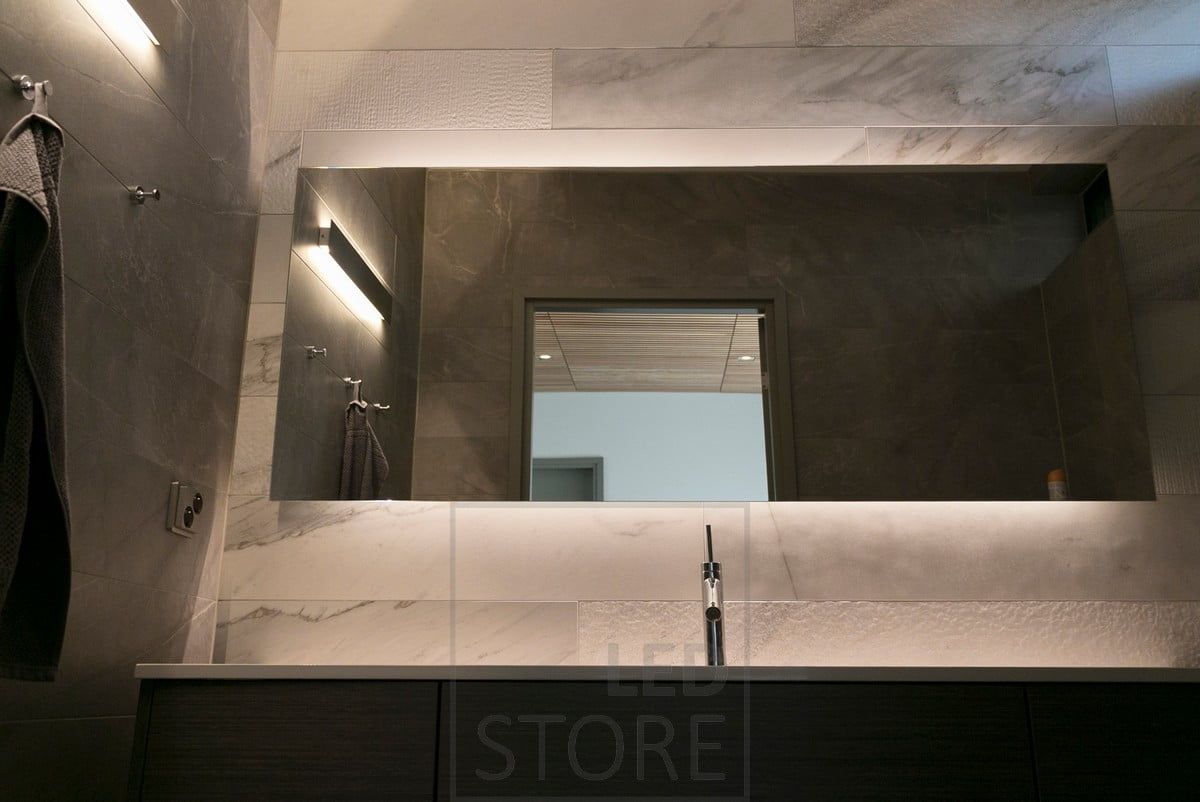 Dietro un bellissimo specchio di grandi dimensioni, una striscia LED mette in risalto lo specchio e crea un'illuminazione d'atmosfera. Inoltre, una lampada da parete bidirezionale. Ledstore.fi