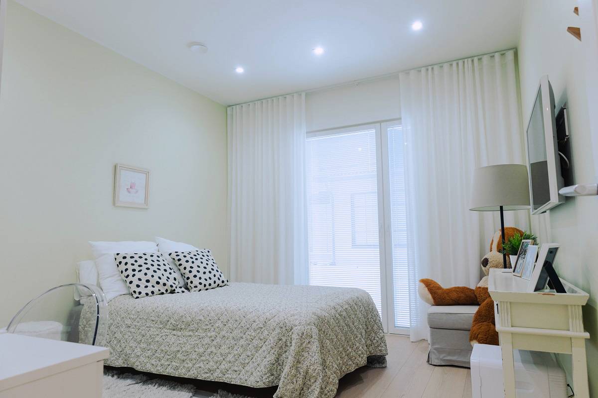 Una camera da letto luminosa e moderna con un letto realizzato con cura, tende bianche e una morbida illuminazione a LED. Dai un'occhiata agli ultimi progetti di riferimento di LedStore.fi per il 2025 e lasciati ispirare per il tuo prossimo progetto di interior design!