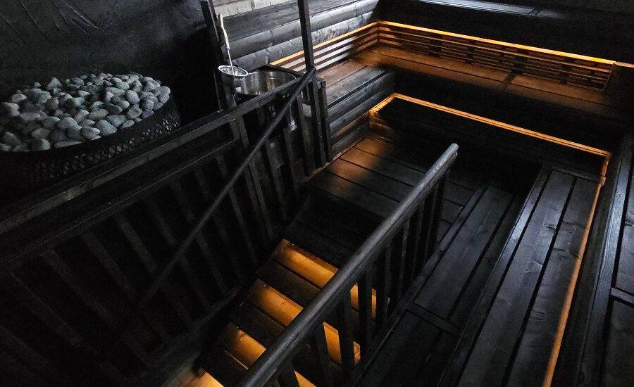 Illuminazione della sauna con striscia LED in profilo di alluminio nella parte inferiore del soffitto e in fondo alle scale, tonalità di luce bianca calda