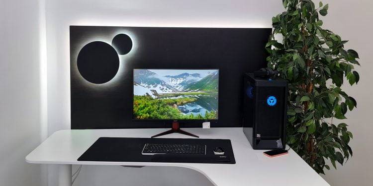 Configurazione minimalista del computer con scrivania bianca curva. Lo schermo mostra uno splendido paesaggio montano, ulteriormente illuminato dalla retroilluminazione a LED. Accanto c'è un PC tower nero con dettagli a LED blu incandescenti. Questo è un esempio di come le soluzioni di illuminazione a LED di LedStore.fi possano dare nuova vita al tuo ufficio o al tuo spazio di lavoro!