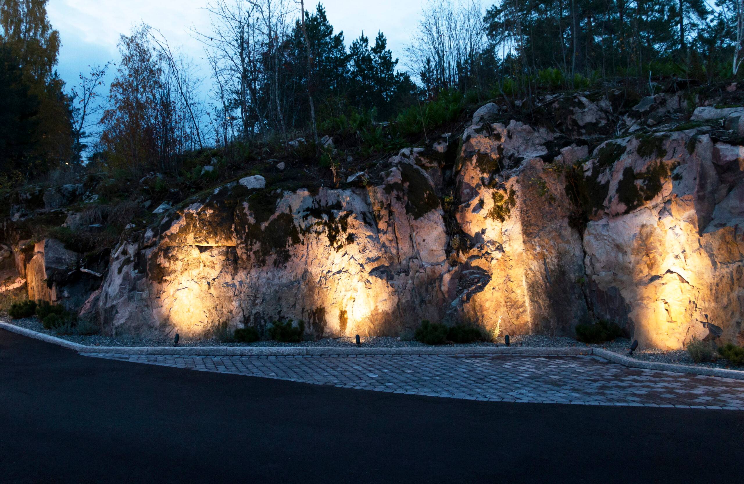 Ai margini del cortile roccioso, le luci paesaggistiche a LED accentuano le forme rigide.