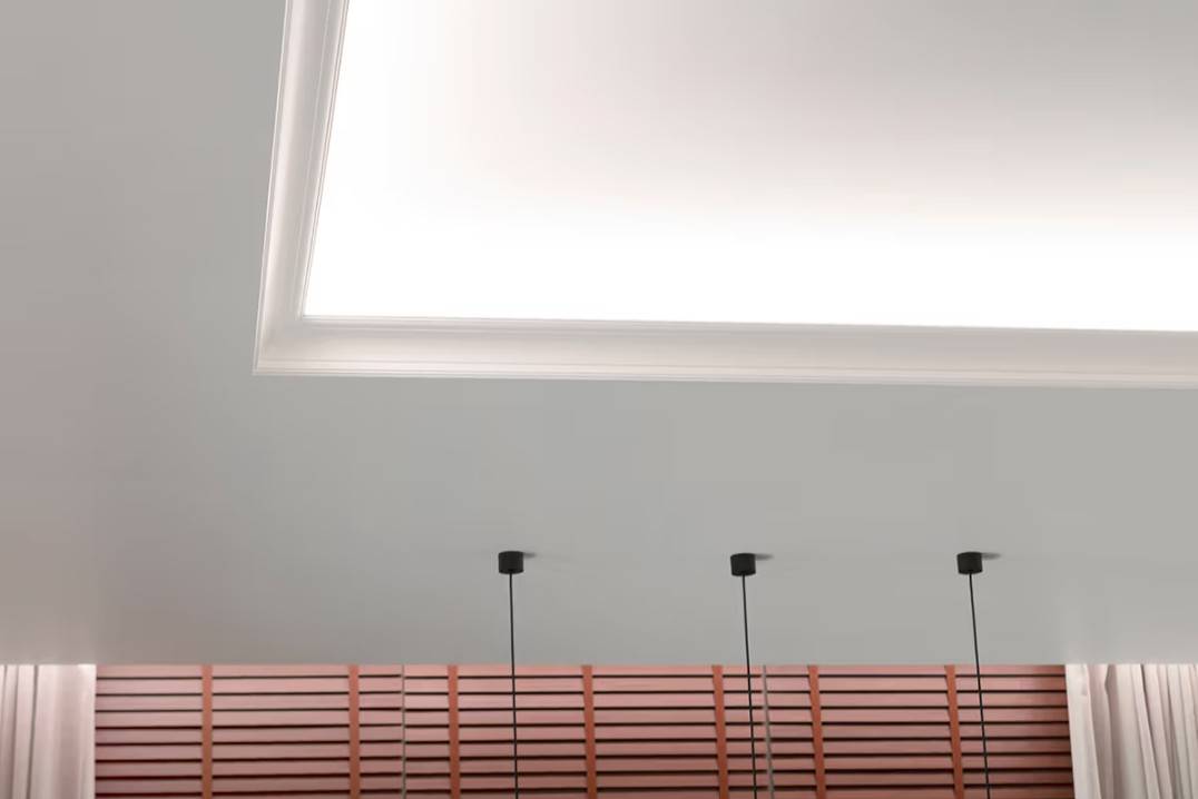 Un pacchetto di illuminazione funzionale per il soggiorno. La striscia LED sulla mensola della plafoniera illumina verso il soffitto e in basso verso le tende.