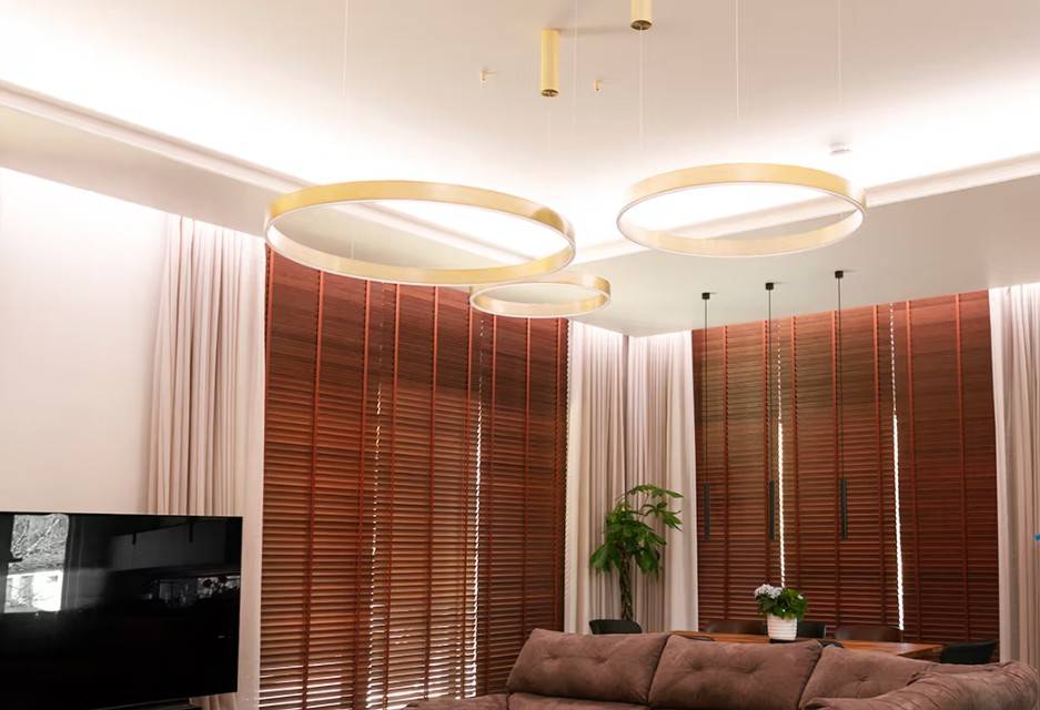 Il moderno soggiorno di famiglia a Kaitamäki, Espoo, è caratterizzato da uno splendido schema di illuminazione LedStore.fi: grandi luci ad anello color oro creano un'atmosfera lussuosa insieme a tende marroni abbinate e a un accogliente divano. Il tutto è completato da un'elegante TV e da una vegetazione rigogliosa: questo è il tipo di illuminazione che rende la tua casa accogliente e suggestiva!