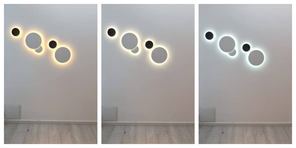 Nel negozio online di LedS.fi puoi trovare diverse serie di applique LED che formano elementi di design circolari di diverse dimensioni, perfetti per le pareti bianche. Ogni apparecchio crea un'atmosfera di luce: giallo caldo, bianco morbido e una luce bluastra più fredda. La parete e il pavimento circostanti sono in tonalità di grigio.