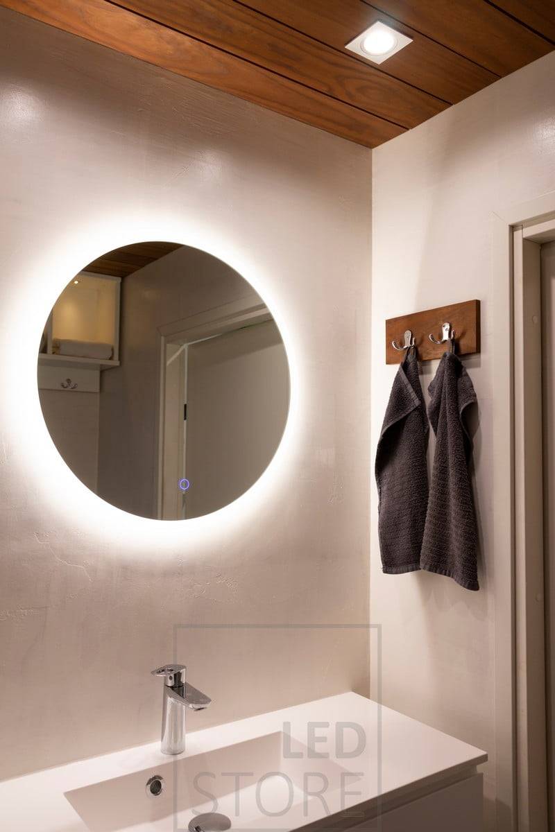 Lo specchio luminoso MOON più piccolo, con un diametro di 600 mm, è ideale per i bagni e le toilette per aggiungere atmosfera e un'illuminazione supplementare (IP55). Il faretto KANTTI sopra lo specchio fornisce una luce diretta sul viso.  Ledstore.fi