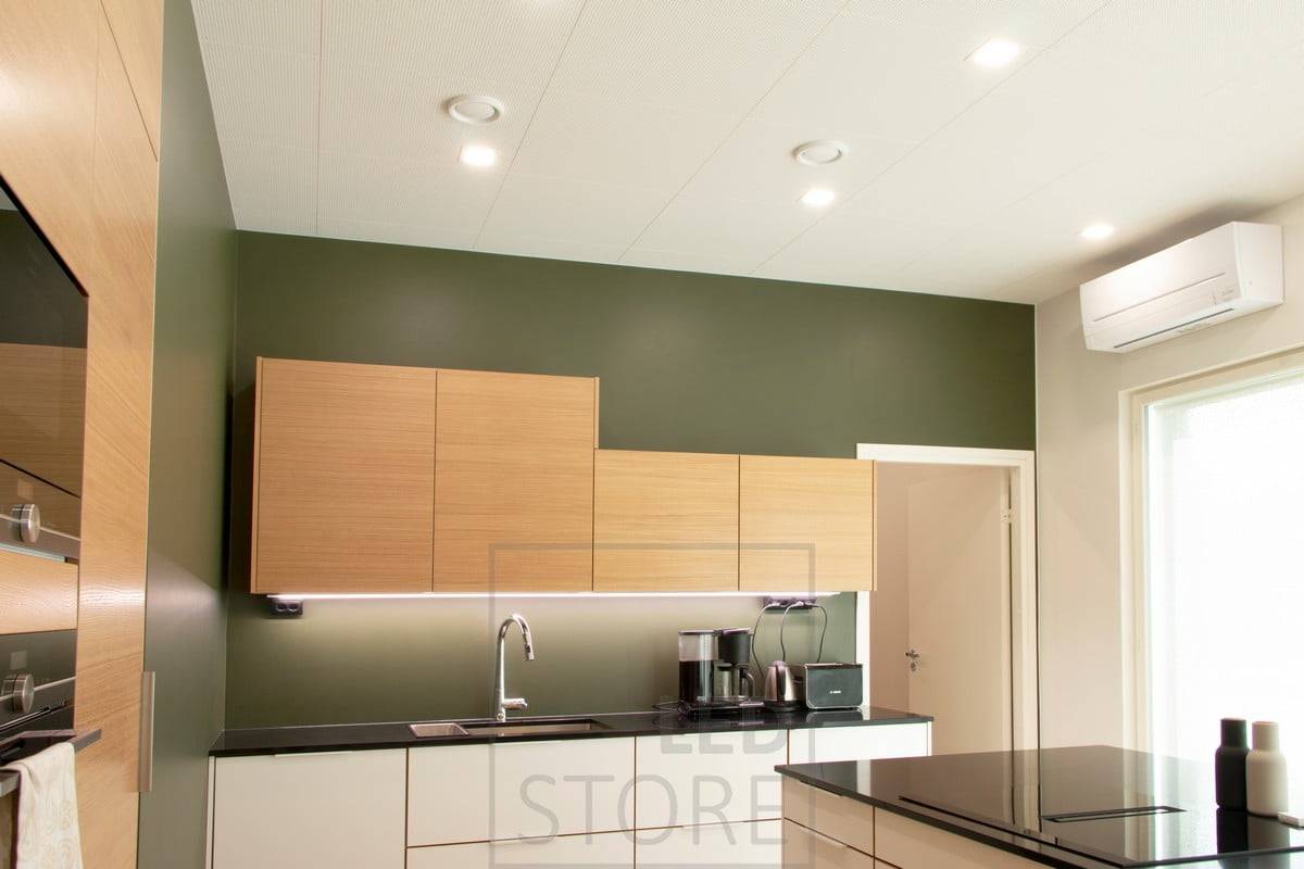 Illuminazione piatta a soffitto in cucina con pannelli LED quadrati e strisce LED alla base degli armadietti superiori come illuminazione piatta. Ledstore.fi