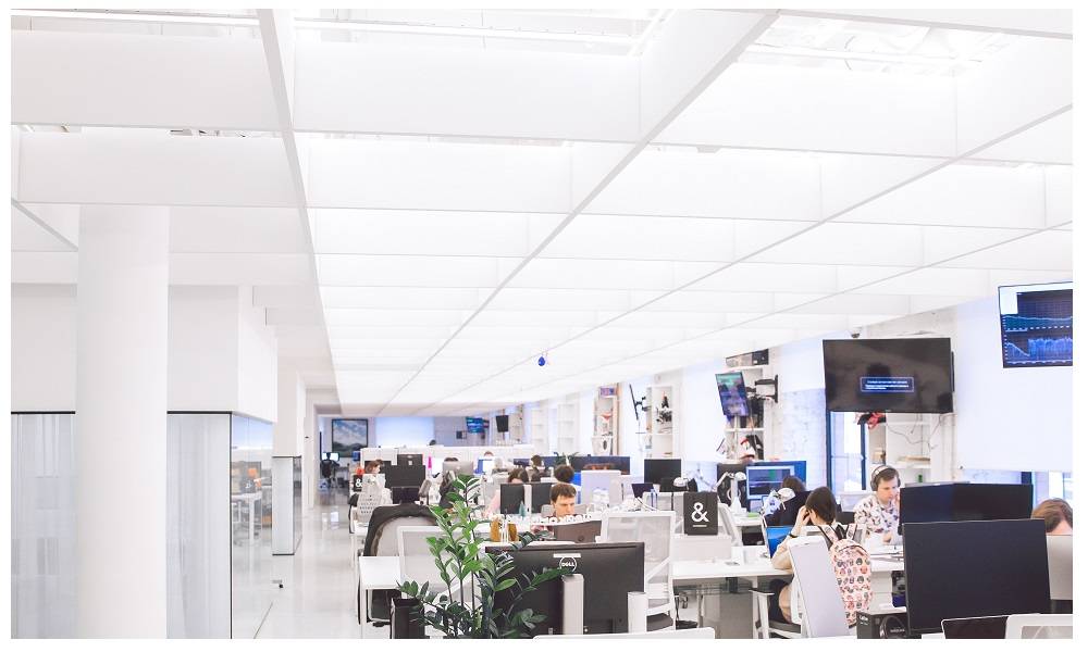Ufficio open space con superfici luminose e luminose e numerose postazioni di lavoro.