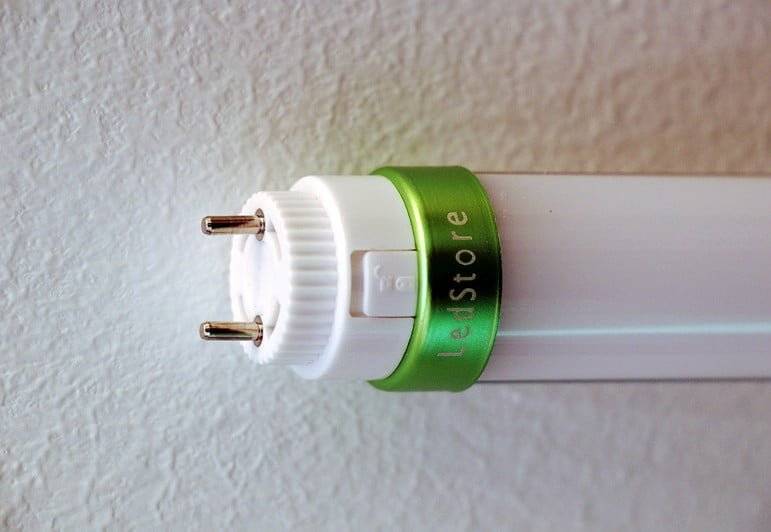 Primo piano del tubo luminoso a LED da un'estremità, che mostra due pin metallici e il logo LedStore.fi.