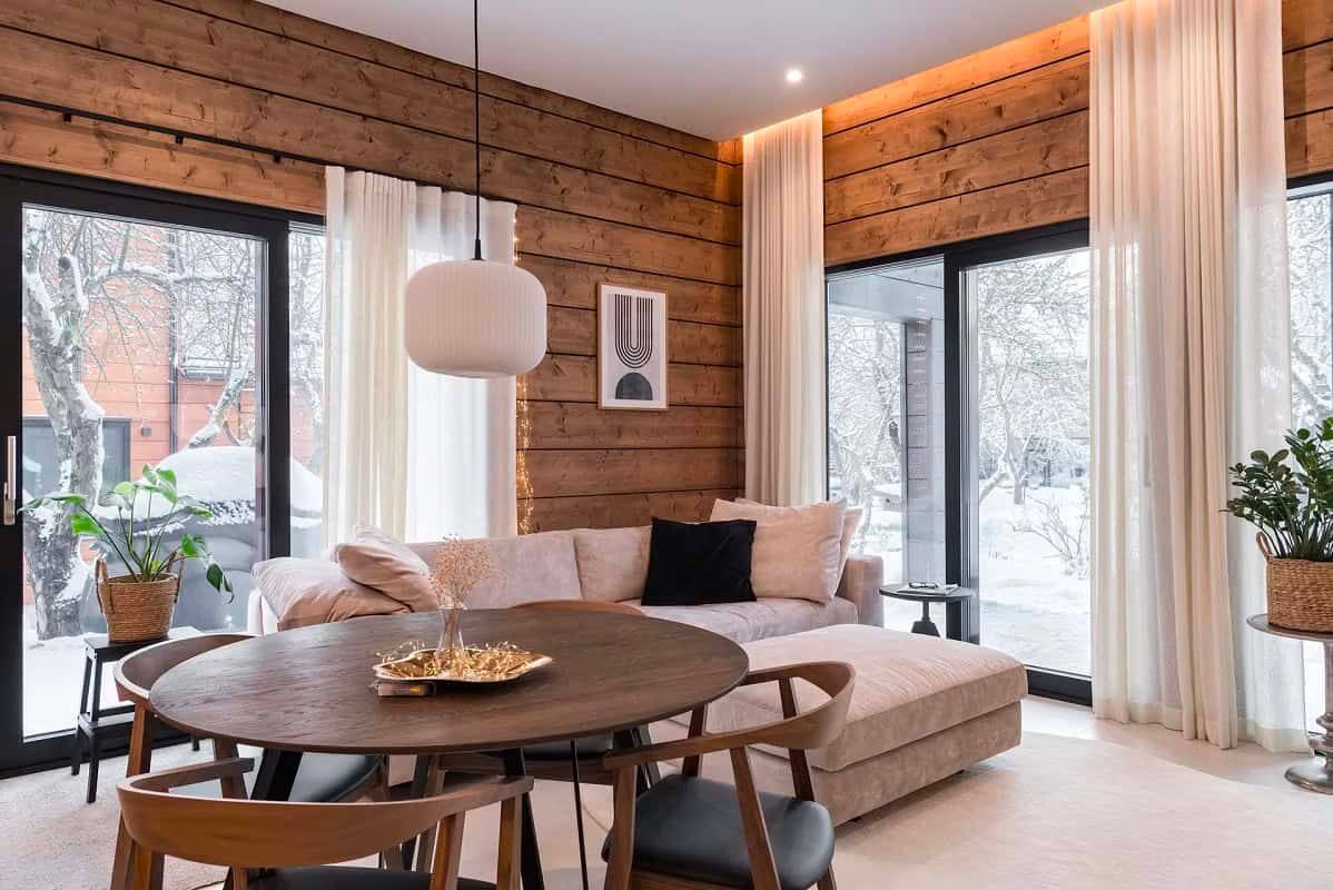 Un soggiorno moderno e caldo con i faretti LED di LedStore.fi che mettono in risalto le superfici in legno e l'architettura dello spazio.