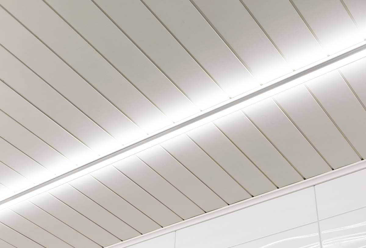 LedStore.fi offre un'illuminazione da soffitto moderna che include, in parallelo, una striscia luminosa a LED centrale. La superficie liscia dei pannelli rettangolari soddisfa perfettamente l'estetica pulita e minimalista dello spazio.