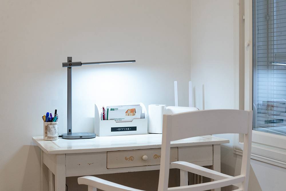 La lampada da tavolo Crane di LedStore illumina una postazione di lavoro leggera.