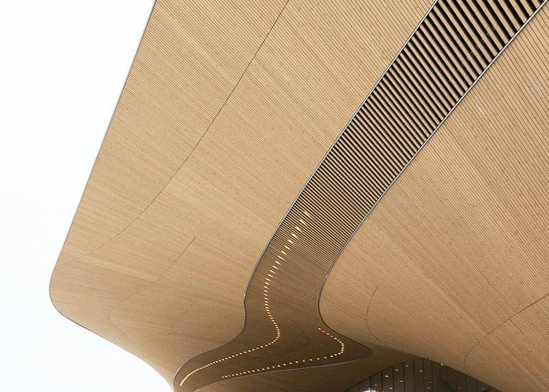 Luce a led nello specchio per il trucco nel backstage di Oodi Una struttura in legno curvato con un design ondulato e luci LED incassate che accentuano il look moderno e astratto su uno sfondo bianco.