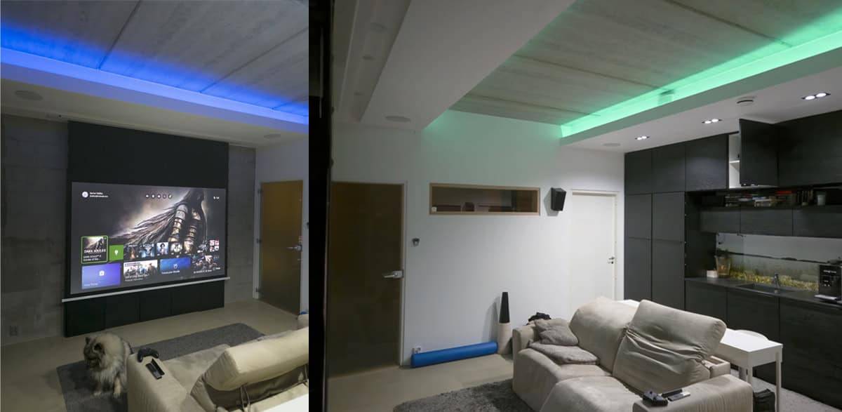 Soggiorno moderno con illuminazione LED LedStore.fi per home theatre, schermo per proiettore, comode sedute e cane a terra.